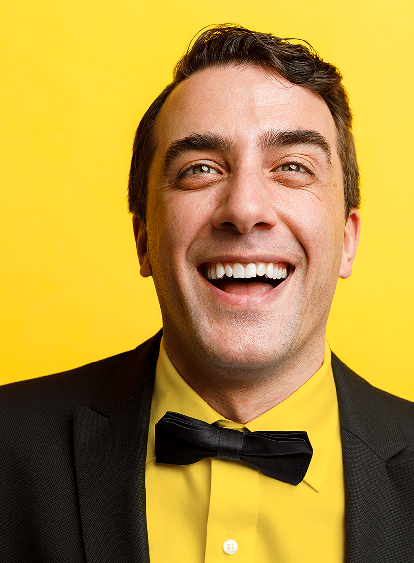 Man wearing a tuxedo and laughing.